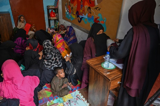 Une sage-femme (d) examine une femme lors d'une consultation dans une clinique sur l'île de Baba, le 6 juin 2024 au Pakistan
