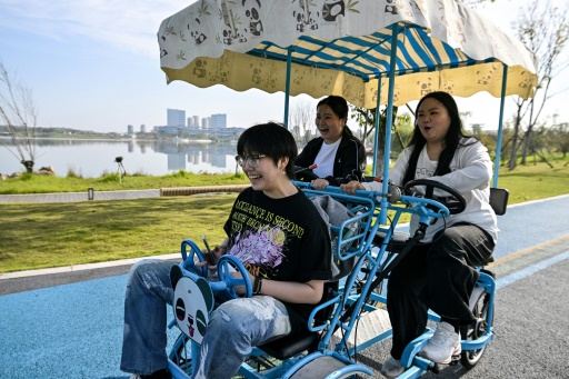 Cette photo prise le 23 octobre 2024 montre Yang Chi'ao (à droite) sur un vélo dans un parc, dans le cadre d'un programme d'entraînement d'un camp d'amaigrissement à Chengdu, dans la province chinoise du Sichuan (sud-ouest)
