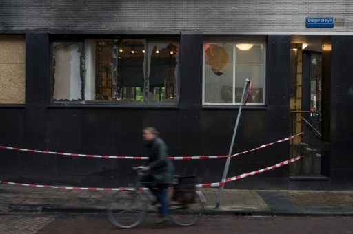 Un cycliste passe, le 23 novembre 2021, devant une facade dégradée par les émeutes contre les restrictions sanitaires à Rotterdam
