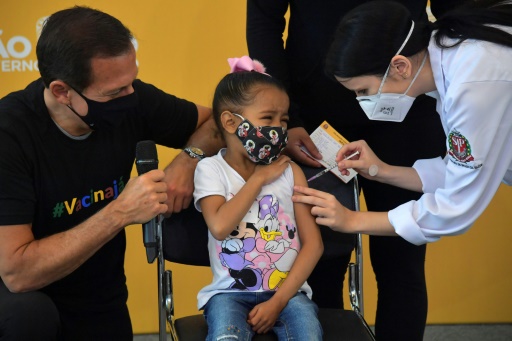 Une enfant reçoit une injection de vaccin contre le Covid-19 en présence du gouverneur de Sao Paulo, Joao Doria (g), le 14 janvier 2022 au Brésil
