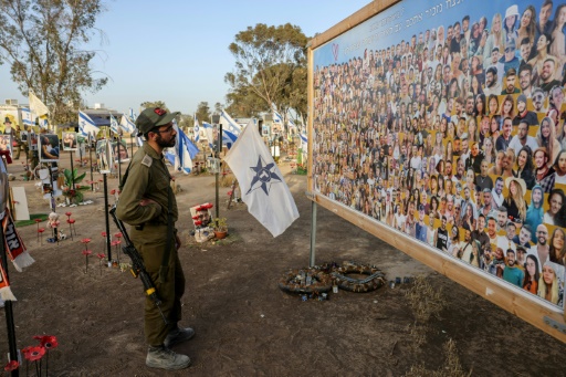 Un soldat israélien regarde un panneau où sont affichées des photos de personnes prises en otage ou tuées durant l'attaque du Hamas contre le festival de musique Supernova le 7 octobre, sur le site du festival près du kibboutz Reim dans le sud d'Israël, le 9 mai 2024
