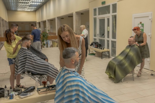 Ioulia Pouzanska, 33 ans (centre), coiffe un militaire ukrainien au Centre de santé mentale Lissova Poliana (La Clairière) de Kiev le 29 août 2024
