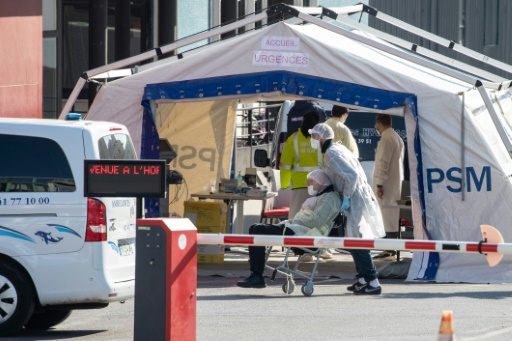 Des médecins s'occupent d'un patient arrivant à l'accueil des Urgences, dans une cour de l'hôpital Henri Mondor à Créteil, près de Paris, le 26 mars 2020, au dixième jour d'un confinement visant à enrayer la propagation du Covid-19 en France
