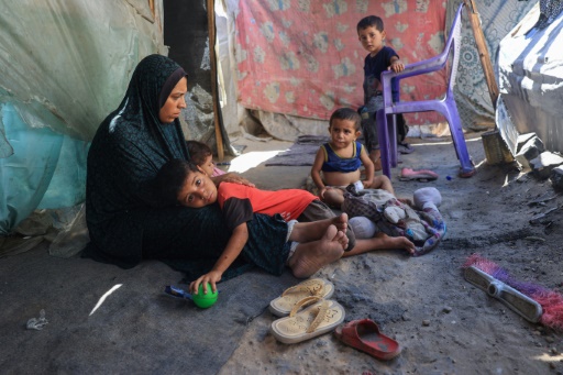 Une mère de famille avec ses enfants dans un camp de déplacés gazaouis à Deir el-Balah, dans le centre du territoire palestinien, le 8 juillet 2024
