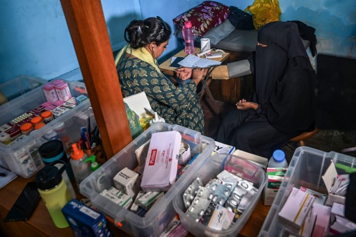 La sage-femme Neha Mankin (g) examine une femme lors d'une consultation dans sa clinique de l'île de Baba, le 6 juin 2024 au Pakistan
