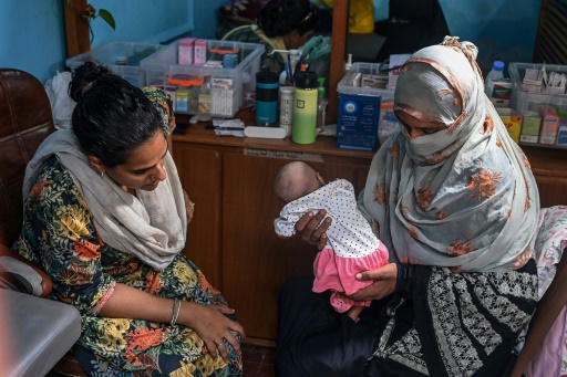 La sage-femme Neha Mankani (g) examine un nourrison dans sa clinique de l'île de Baba, le 6 juin 2024 au Pakistan
