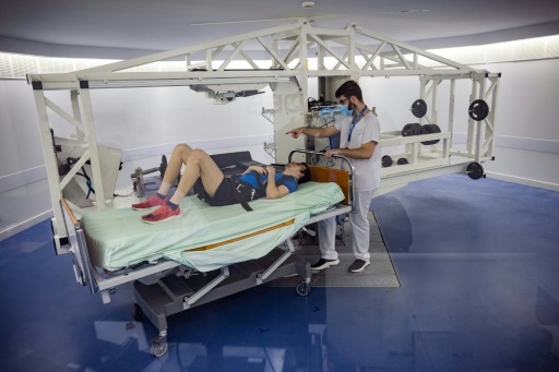 Un volontaire allongé sur une centrifugeuse est examiné par un médecin lors d'une expérience à la clinique de Medes, filiale santé du Centre national d'études spatiales (CNES), à Toulouse, le 23 mai 2023
