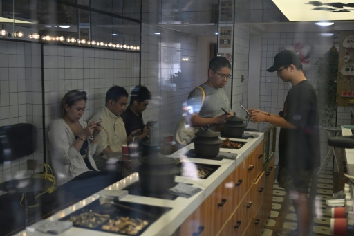 Un client (c) achète de la tisane dans un café du district de Xuhui, le 6 août 2024 à Shanghai
