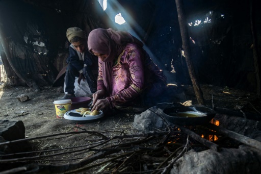 Une femme cuisine sur un feu de brindilles, dans le camp de réfugiés de Al-Younani, dans les environs de Raqa, en Syrie, le 8 février 2024
